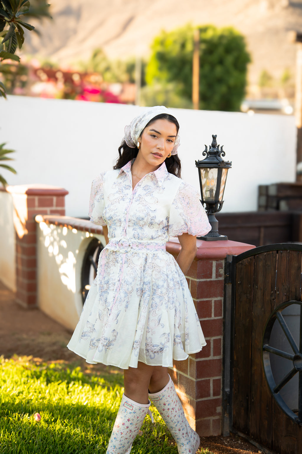Model wearing the Camila Bella Dress in ivory with blush pink and blue paisley florals, flutter sleeves and a braided waist belt