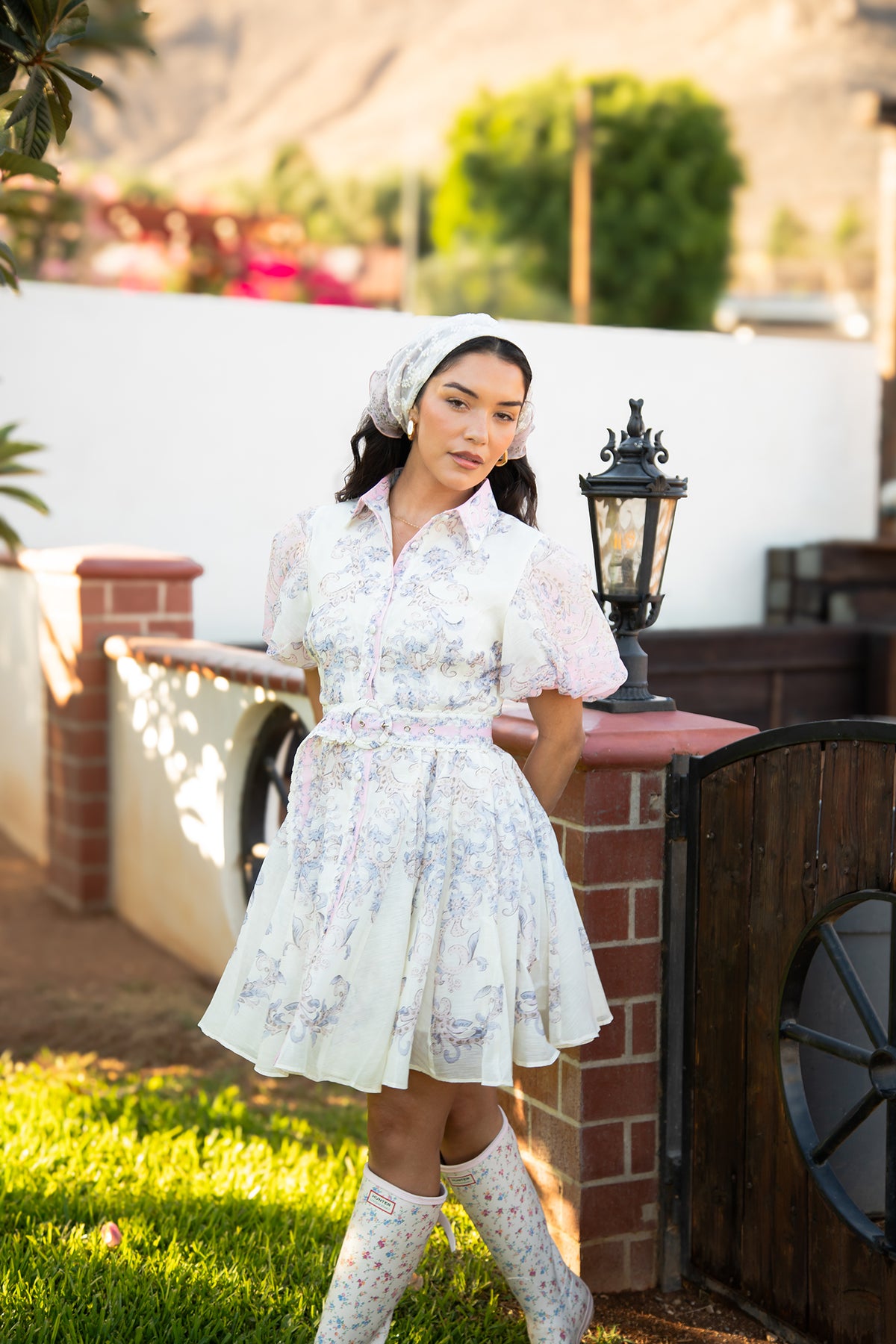 Model wearing the Camila Bella Dress in ivory with blush pink and blue paisley florals, flutter sleeves and a braided waist belt