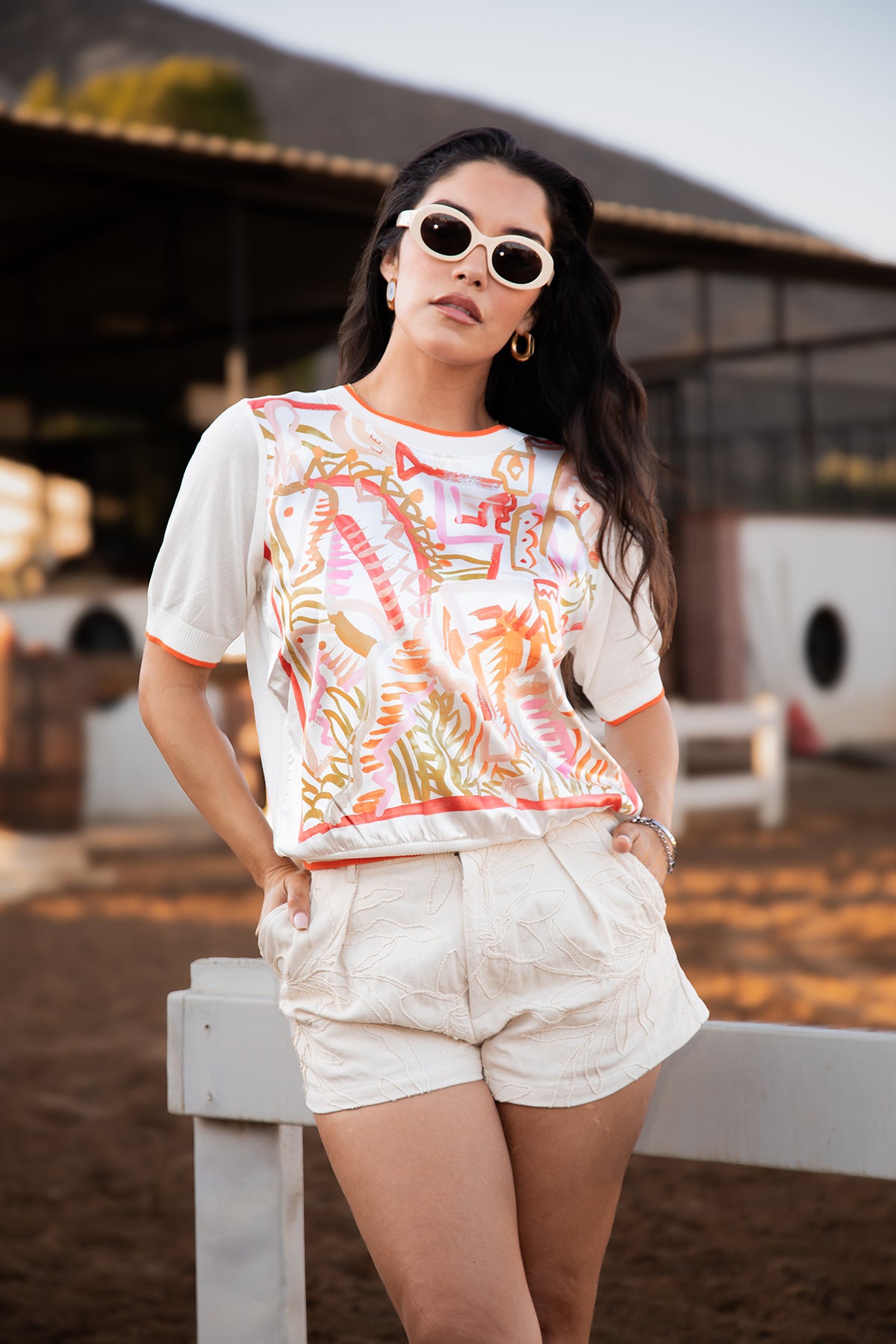 Model wearing the Ecuestre Silk Satin Top with an abstract coral, orange and caramel print