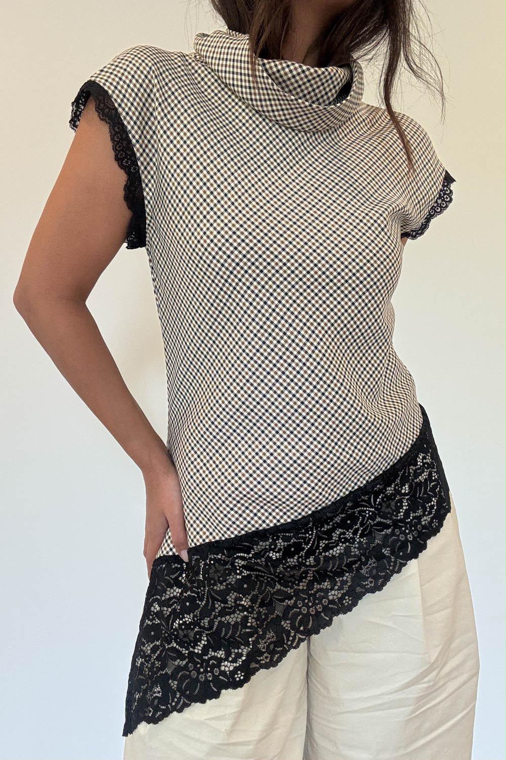 Model wearing the Arianna Lace Top, a mini check top with cowl neck and asymmetric black lace hem
